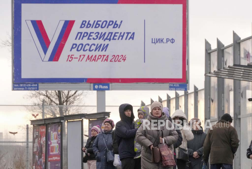 Orang-orang menunggu bus di halte bus di sebelah papan reklame yang mempromosikan pemilihan presiden mendatang dengan kata-kata dalam Pemilihan Presiden Rusia di Rusia. 