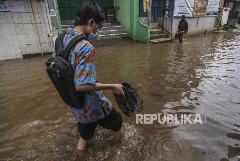 Warga melintasi genangan banjir di Kampung Utan, Citayem, Depok, Jawa Barat, Senin (8/2/2021). Banjir setinggi 30 cm - 50 cm tersebut disebabkan karena meluapnya aliran kali dan hujan deras yang mengguyur Kota Depok. 