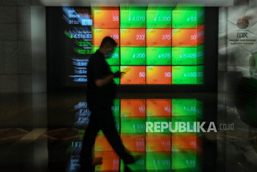 Pekerja melintas di depan layar yang menampilkan informasi pergerakan harga saham di gedung Bursa Efek Indonesia (BEI), Jakarta. ilustrasi