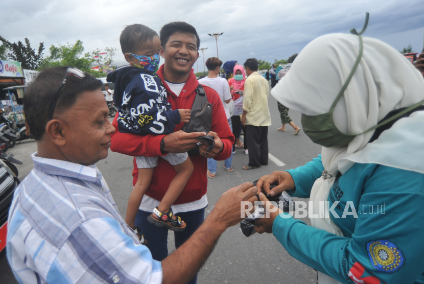 Petugas membagikan masker kepada warga, di Pantai Padang, Sumatra Barat, Senin (17/8/2020).  Penambahan jumlah kasus positif Covid-19 di Sumbar pada Sabtu (5/9) disumbang oleh warga di 10 daerah kabupaten kota.  