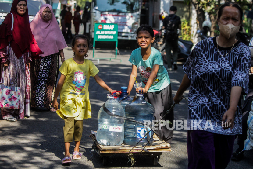 Warga membawa galon berisi air saat pendistribusian air bersih di kawasan Cengkareng, Jakarta Barat.