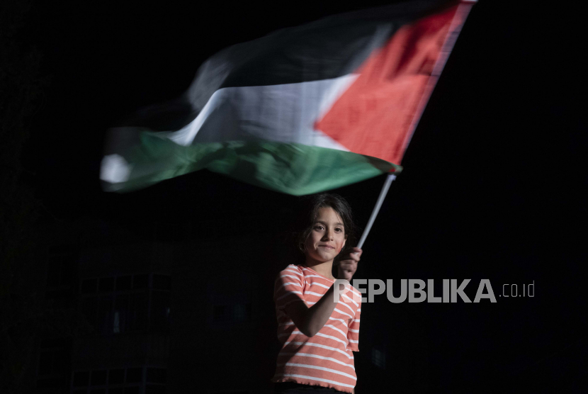 Seorang gadis mengibarkan bendera Palestina.