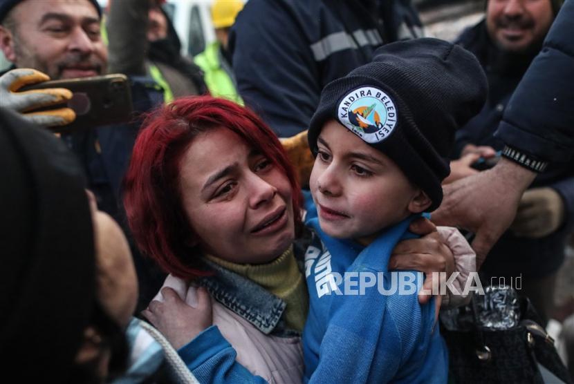 Yigit Cakmak (kanan) yang berusia delapan tahun digendong oleh ibunya setelah diselamatkan dari lokasi bangunan yang runtuh, sekitar 52 jam setelah gempa besar, di Hatay, Turki,Rabu (8/2/2023). Lebih dari 7.000 orang tewas dan meninggal dunia. ribuan lainnya terluka setelah dua gempa besar melanda Turki selatan dan Suriah utara pada Senin (6/2/2023).