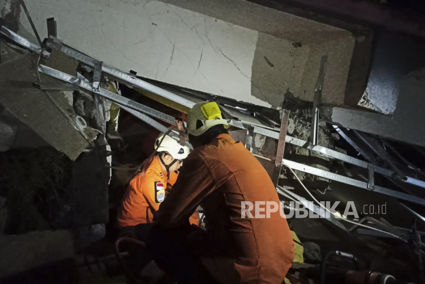  Gambar selebaran yang disediakan oleh Badan Pencarian dan Penyelamatan Nasional Indonesia (BASARNAS) menunjukkan penyelamat mencari korban di bawah reruntuhan bangunan yang runtuh setelah gempa berkekuatan 6,2 di Mamuju, Sulawesi Barat, Indonesia, 15 Januari 2021. Setidaknya tiga orang tewas dan puluhan luka-luka.