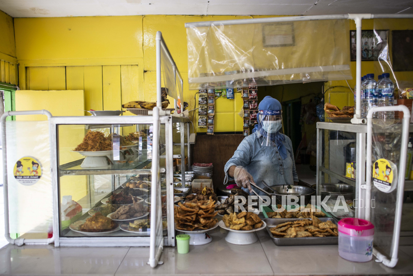 Pelayan menggunakan masker, sarung tangan dan pelindung wajah saat melayani pelanggan di Warung Tegal (Warteg). ilustrasi
