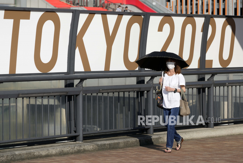  Seorang wanita menggunakan payung untuk melindungi dirinya dari sinar matahari di Tokyo, Jepang, 25 Juli 2021. Kondisi panas yang parah mempengaruhi para atlet karena suhu mencapai 35 derajat dengan kelembaban melebihi 70 persen di Olimpiade Tokyo 2020.
