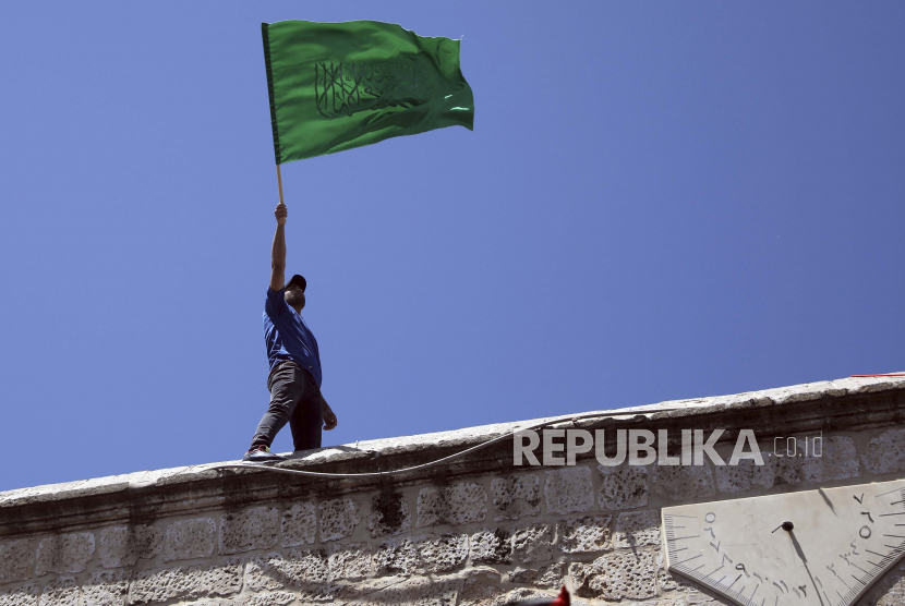 Seorang jamaah mengibarkan bendera Hamas selama protes terhadap kemungkinan penggusuran keluarga Palestina dari rumah, setelah shalat Jumat terakhir bulan suci Ramadhan di Masjid Kubah Batu di kompleks Masjid Al Aqsa di Kota Tua. Yerusalem, Yerusalem, Jumat, 7 Mei 2021.