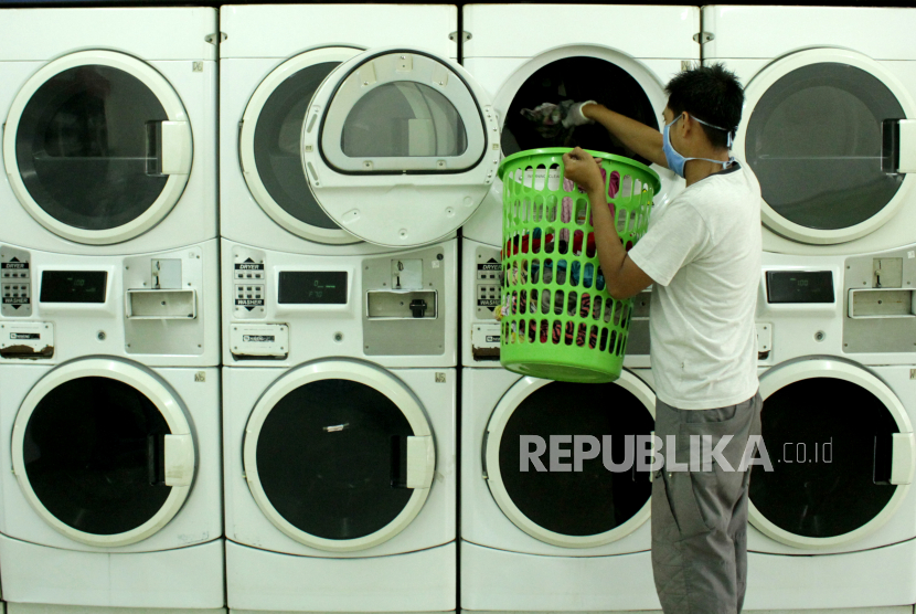 Karyawan memasukkan pakaian ke dalam mesin cuci di salah satu tempat usaha laundry. ilustrasi