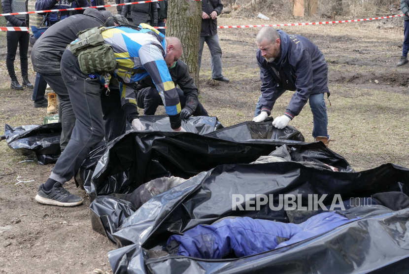 Relawan mengumpulkan mayat warga sipil yang terbunuh, di Bucha, dekat Kyiv, Ukraina, Senin, 4 April 2022. Sekutu Barat akan menyepakati sanksi baru buat Rusia dalam beberapa hari ke depan karena korban sipil bertambah.