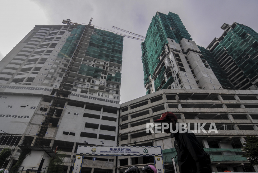 Warga melintas dengan latar belakang proyek pembangunan hunian Transit Oriented Development (TOD) di kawasan Tanjung Barat, Jakarta, Rabu (15/7). Melihat pertumbuhan kuartalan, Indonesia sebenarnya sudah mengalami resesi. 