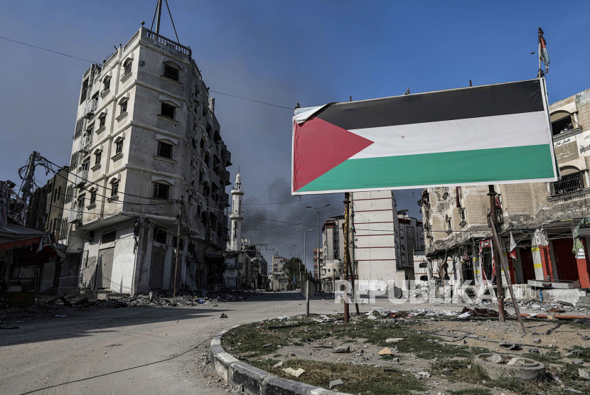 Sebuah papan iklan dengan bendera Palestina berdiri di samping bangunan yang rusak setelah serangan udara Israel di lingkungan Tel al-Hawa, di Kota Gaza, 30 Oktober 2023.