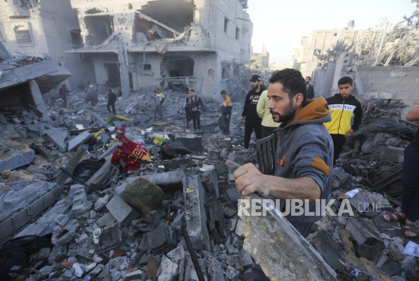 Warga Palestina berdiri di dekat bangunan yang hancur akibat pengeboman Israel di Rafah, Jalur Gaza, Jumat, 24 November 2023.