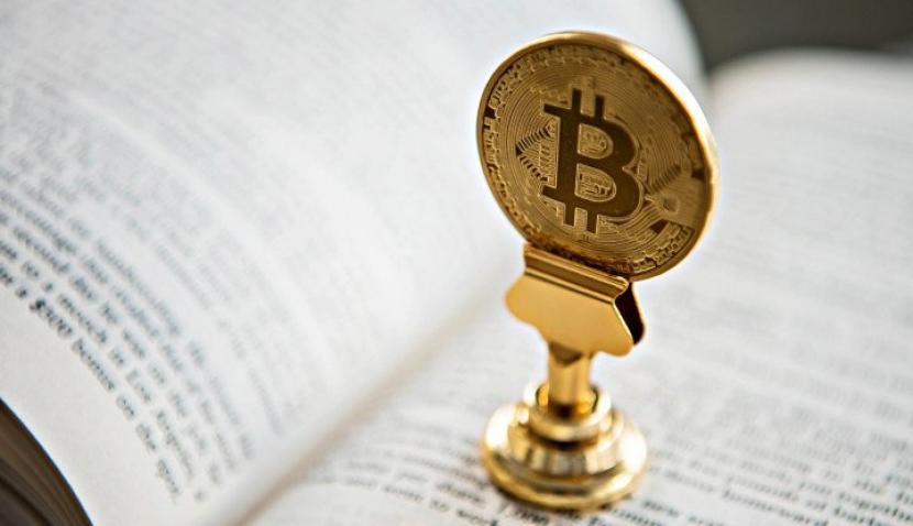 Logo bitcoin berada di atas sebuah buku. (Unsplash/André François McKenzie)