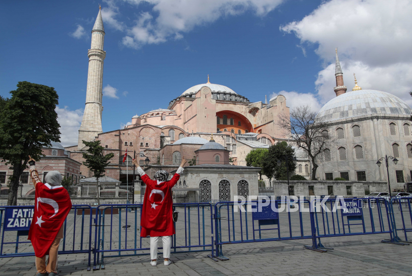 Wanita memegang bendera Turki di depan Museum Hagia Sophia di Istanbul, Turki, 10 Juli 2020. Pengadilan administrasi tertinggi Turki pada 10 Juli 2020 memutuskan bahwa museum yang dulunya masjid yang dibangun di katedral dapat diubah menjadi masjid lagi dengan menganulir. statusnya sebagai museum. 