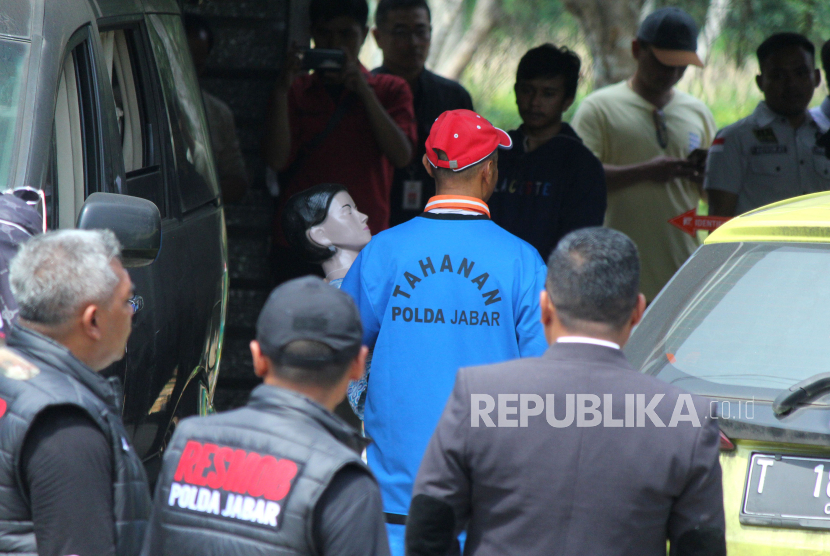 Tersangka Yosep Hidayah (topi merah) melakukan salah satu adegan saat rekontruksi kasus pembunuhan yang merenggut nyawa istri dan anaknya, yaitu Tuti Suhartini dan Amalia Mustika Ratu, di rumah kejadian perkara (TKP), di Jalan Cagak Subang, Kabupaten Subang, Jawa Barat, Rabu (22/11/2023). Dalam rekontruksi yang digelar jajaran Kepolisian Ditreskrimum Polda Jabar ini memeragakan 95 adegan yang menggambarkan proses pembunuhan oleh para tersangka.
