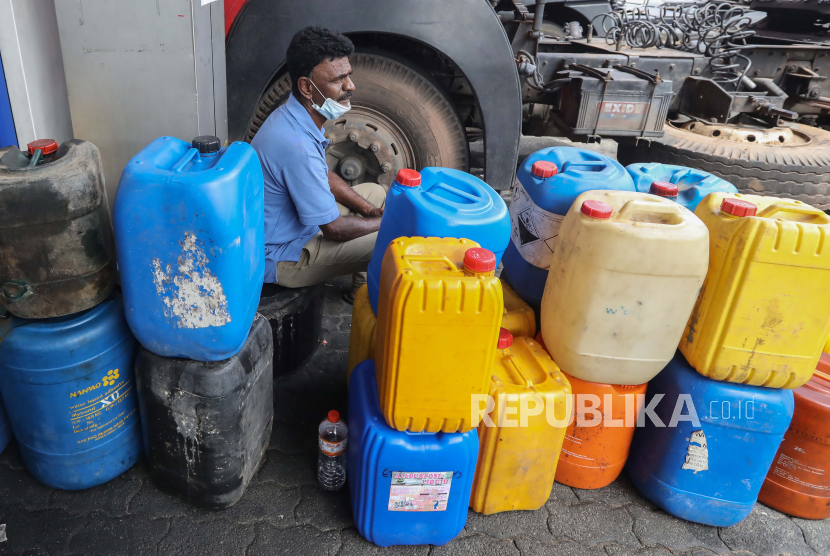 Seorang pria duduk di sebelah kaleng bensin di sebuah pompa bensin di tengah kekurangan bahan bakar di Kolombo, Sri Lanka, 17 Mei 2022.