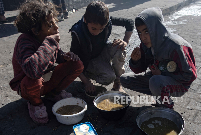 Anak-anak pengungsi Palestina makan menggunakan tangan mereka makanan yang disediakan oleh kelompok pemuda Palestina, di kamp pengungsi Rafah, Jalur Gaza selatan, (1/2/2024). 
