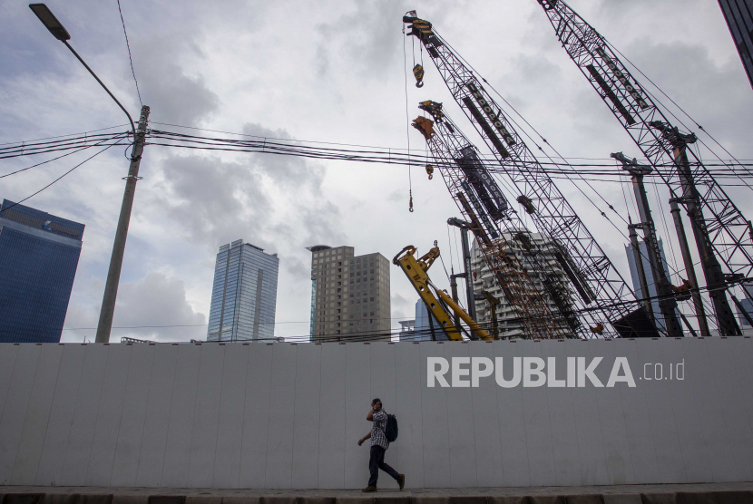 Warga berjalan dengan latar belakang proyek pembangunan gedung bertingkat di kawasan Bendungan Hilir, Jakarta, Selasa (20/10/2020). Gelombang kedua Covid-19 dinilai akan menghambat proses pemulihan ekonomi global pada tahun depan.
