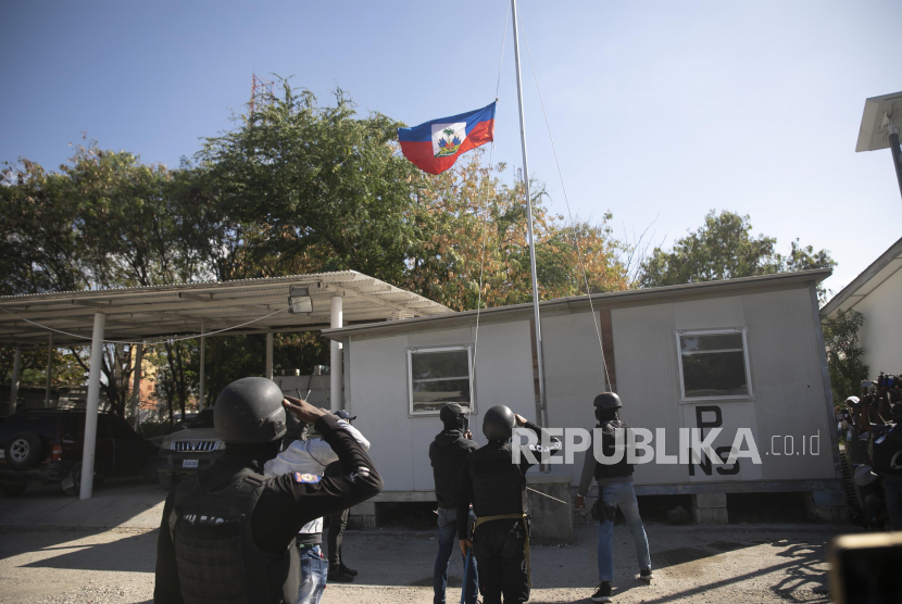 Petugas polisi memberi hormat kepada bendera Haiti setengah tiang di dalam kompleks markas polisi di Port-au-Prince, Haiti, Kamis, 26 Januari 2023.