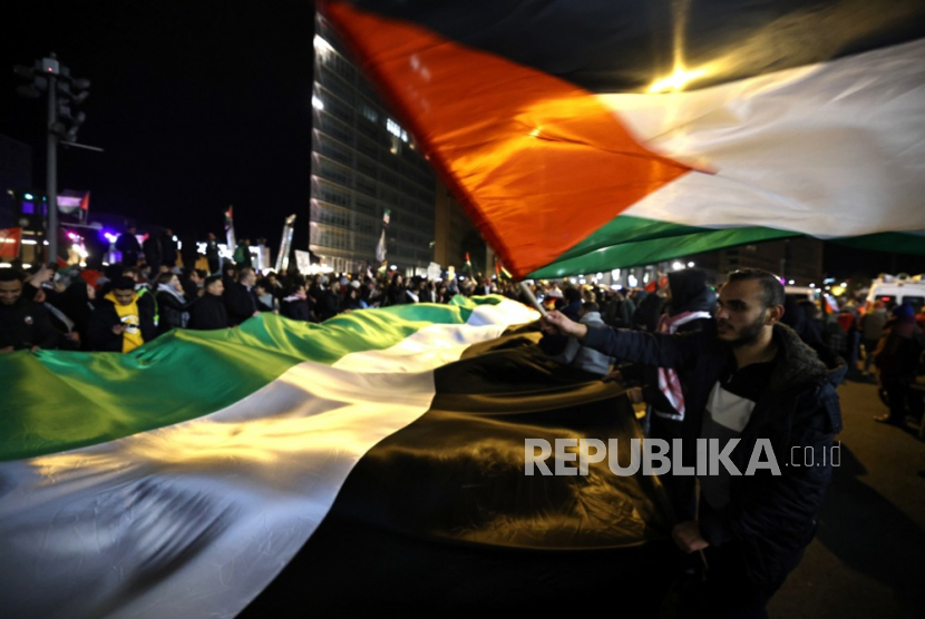 Para pengunjuk rasa memegang bendera raksasa Palestina saat aksi solidaritas dengan Palestina, di Berlin, Jerman, Ahad (5/11/2023).