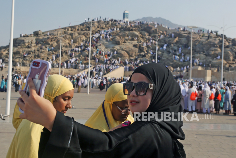 Jamaah umrah asal Indonesia berswafoto dengan latar belakang Jabal Rahmah di Mekkah, Arab Saudi, Sabtu (3/12/22022). Jabal Rahmah adalah salah satu tempat yang dikunjungi umat muslim usai menjalankan ibadah umroh untuk berwisata religi yang di atas bukit terdapat monumen yang menjadi simbol bertemunya Adam dan Hawa. 