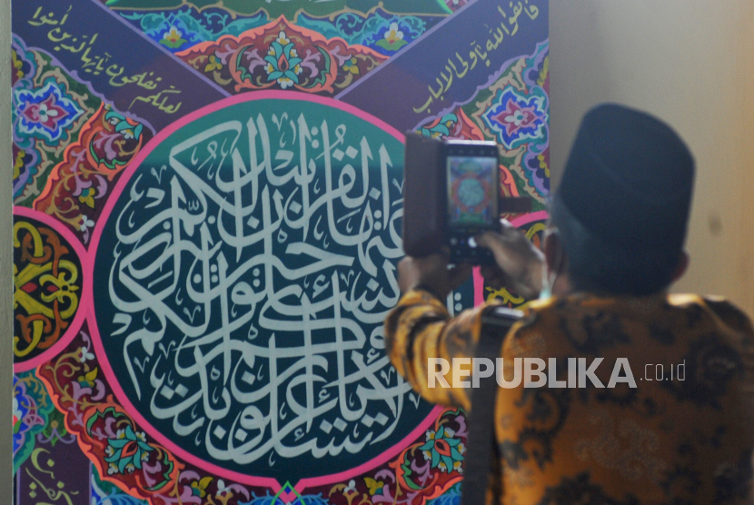 Pengunjung memotret hasil karya Lomba Cabang Khat (Kaligrafi) Al Quran, MTQ Nasional ke-28, di GOR UNP, Padang, Sumatera Barat, Selasa (17/11/2020). Cabang seni kaligrafi Al Quran adalah salah satu dari 8 cabang yang dilombakan pada MTQ Nasional ke-28. 