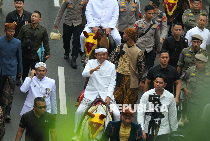 Gubernur Jawa Barat (Jabar) Dedi Mulyadi menunggang kuda menyapa warga saat kirab budaya atau karnaval Jabar Hudang dalam rangka perayaan HUT Provinsi Jawa Barat (Jabar) ke-80, di Kota Bandung, Selasa (19/8). Karnaval yang diikuti seluruh kota dan kabupaten di Jabar ini mengangkat spirit kebangkitan hasil pertanian, industri dan UMKM lokal.