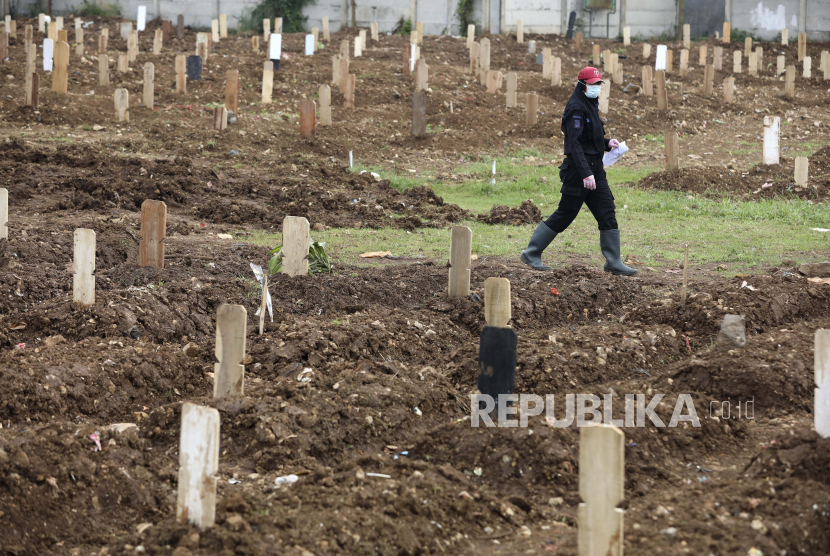  Seorang karyawan berjalan di antara kuburan di bagian khusus pemakaman Srengseng Sawah yang dibuka untuk menampung lonjakan kematian selama wabah virus Corona di Jakarta, Indonesia, Senin, 25 Januari 2021. Indonesia telah melaporkan lebih banyak kasus virus daripada yang lain. negara di Asia Tenggara.