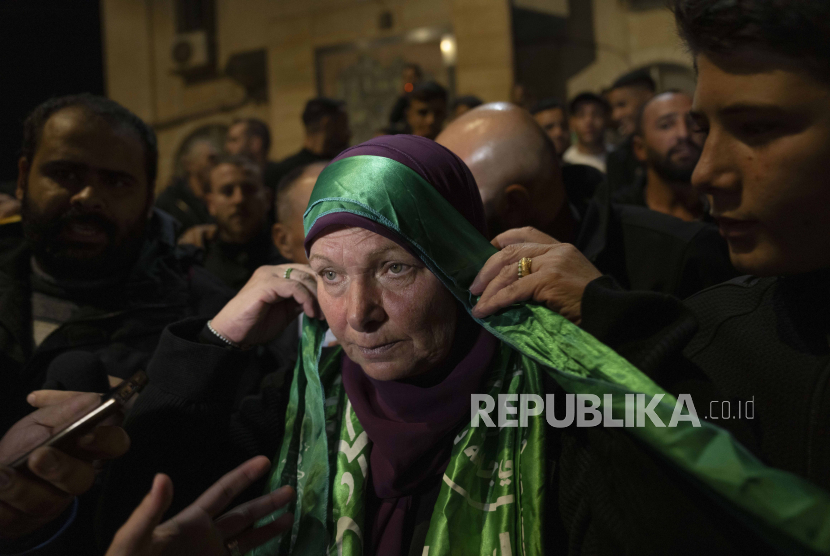 Mantan tahanan wanita Palestina Hanna Barghouti, yang dibebaskan oleh otoritas Israel, mengenakan ikat kepala Hamas saat dia diterima oleh para pendukungnya setibanya di kota Beitunia, Tepi Barat, Jumat (24/11/2023). Israel dan Hamas sepakat untuk melakukan pembebasan sandera sebagai bagian dari perjanjian gencatan senjata selama empat hari. Sebanyak 50 sandera Israel dibebaskan oleh Hamas dan 150 wanita Palestina serta anak-anak yang ditahan di penjara Israel dibebaskan oleh Israel. 