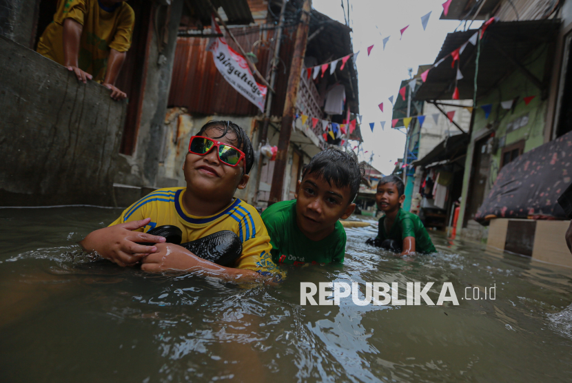 Anak-anak bermain saat banjir rob menggenangi permukimannya di kawasan Muara Angke, Jakarta Utara, Kamis (6/11/2025).