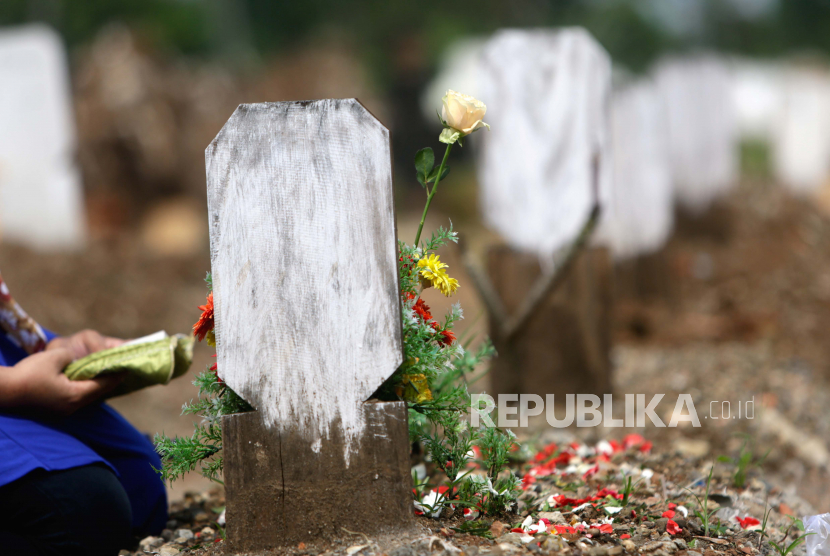 Seorang wanita berdoa di depan kuburan ibunya di pemakaman (ilustrasi)