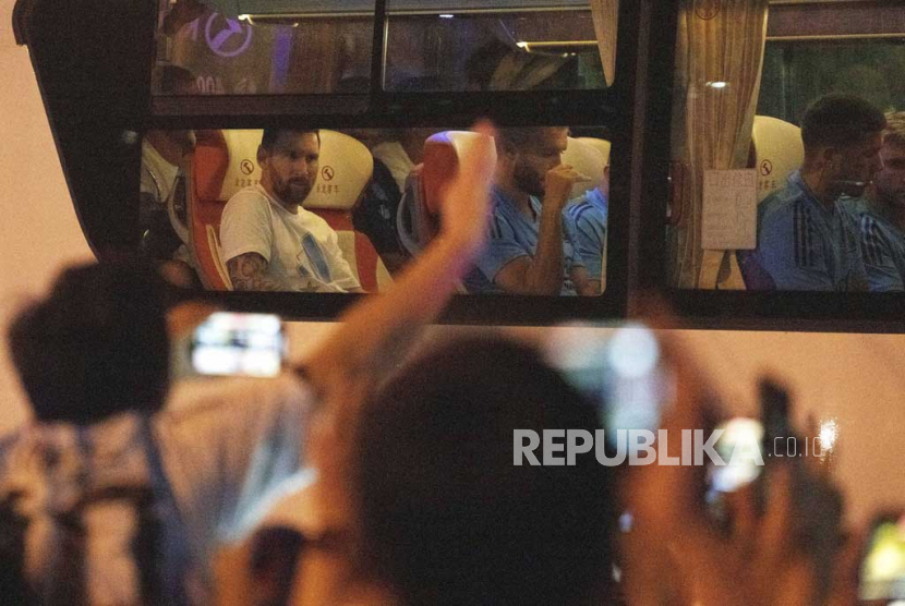 Para penggemar berteriak saat mereka melihat sekilas Lionel Messi, mengenakan pakaian putih (kiri)  dan anggota tim sepak bola nasional Argentina lainnya saat mereka kembali ke hotel mereka dengan bus di Beijing, Senin, (12/6/2023).