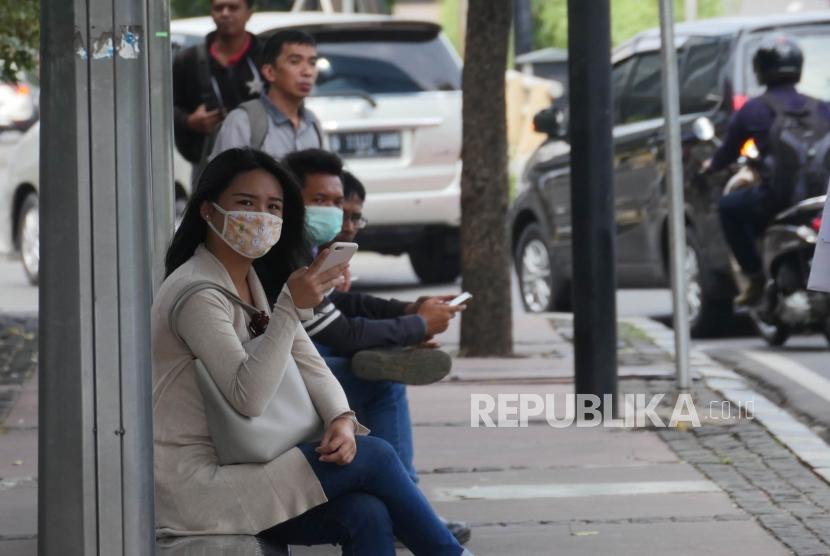 Warga  menunggu angkutan umum di halte bus, di jalan Jenderal Sudirman Jakarta, Jumat (22/6).