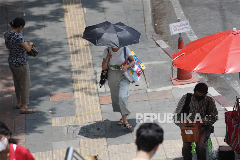  Seorang wanita melindungi diri dari sinar matahari di bawah payung saat cuaca panas.