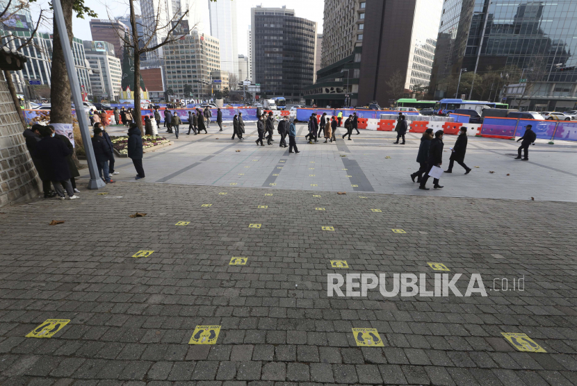  Orang melewati tanda jarak sosial di depan Istana Deoksu di Seoul, Korea Selatan, Senin, 7 Desember 2020. Kasus virus corona Korea Selatan naik di atas 1.000 lagi dalam 24 jam pada Jumat (1/1).
