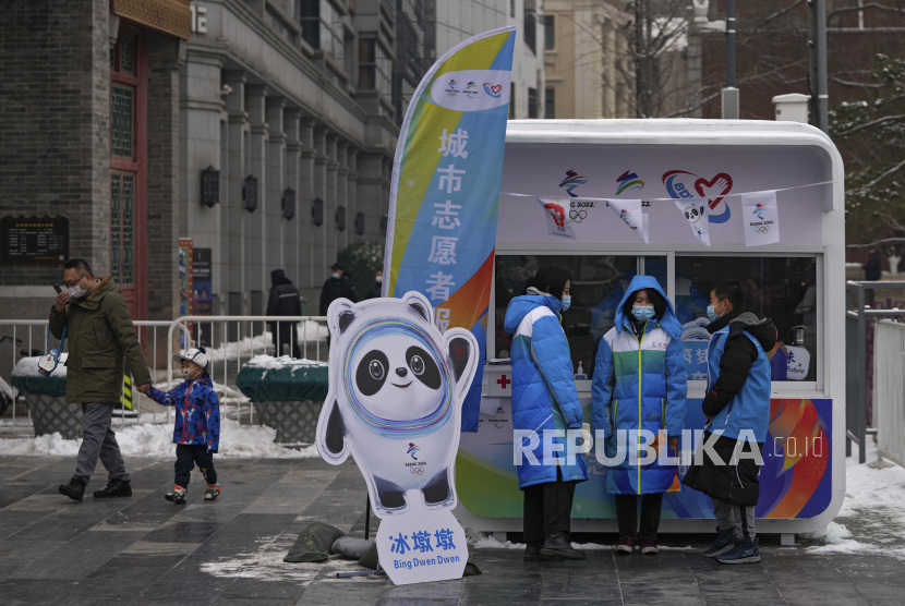 Relawan yang mengenakan masker wajah untuk membantu melindungi dari virus corona mengobrol satu sama lain di stan informasi untuk Olimpiade Musim Dingin Beijing di Qianmen Street, tempat wisata populer di Beijing, akhir pekan lalu.