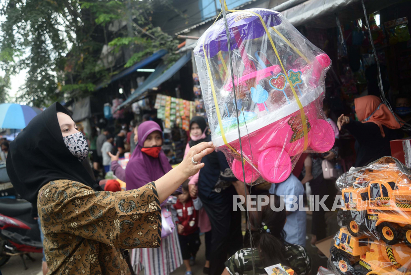 Orang tua memilih mainan yang dijual untuk anaknya di Pasar Gembrong, Jakarta , Selasa (26/5). Meski masa Pembatasan Sosial Berslaka Besar (PSBB) di Jakarta masih berlaku, aktivitas tempat yang menawarkan berbagai macam mainan anak dengan harga terjangkau tersebut ramai dikunjungi warga pascalebaran.