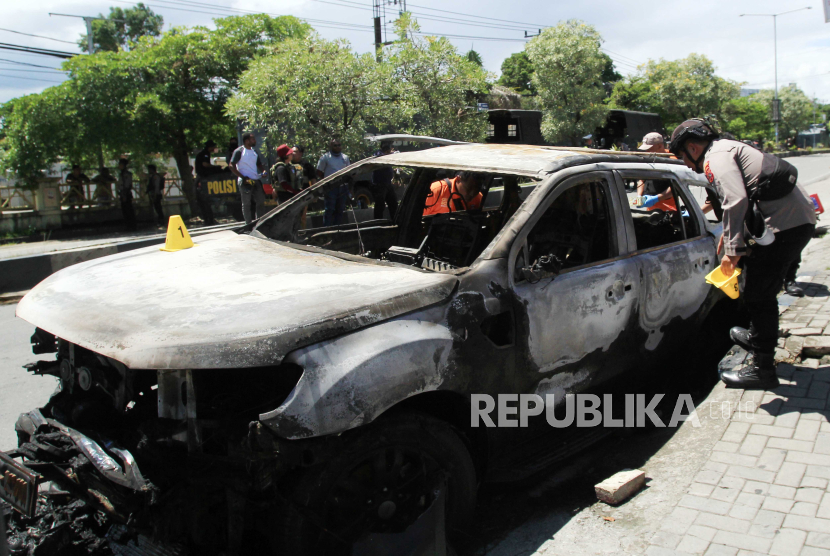 Polisi melihat kondisi mobil yang dibakar massa di Sentani, Kabupaten Jayapura, Papua, Kamis (28/12/2023).  Arak-arakan saat prosesi pemakaman mantan Gubernur Papua Lukas Enembe diwarnai kericuhan massa yang membakar mobil dan menyerang aparat. 