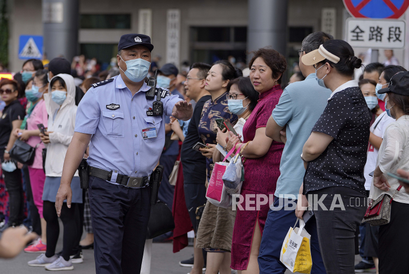 Seorang polisi yang mengenakan masker untuk membantu mengekang penyebaran virus corona meminta kerabatnya untuk mundur ketika para siswa memasuki sekolah untuk ujian masuk perguruan tinggi nasional China, yang dikenal sebagai gaokao, di Beijing, Senin, 7 Juni 2021. 