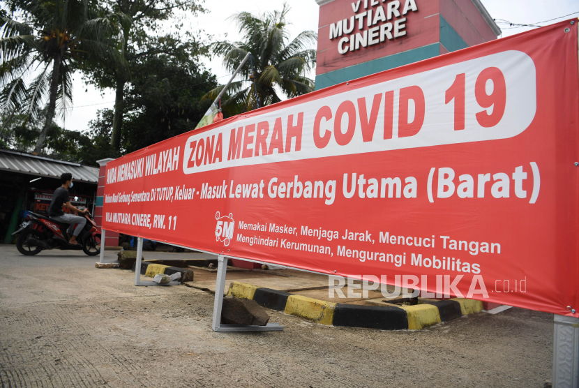 Seorang pengendara melintas di dekat spanduk pemberitahuan lokasi zona merah COVID-19 di Depok, Jawa Barat, Rabu (7/7/2021). Satgas Penanganan COVID-19 mengimbau masyarakat untuk mengurangi mobilitas di daerah aglomerasi saat PPKM Darurat untuk mencegah penyebaran COVID-19 di mana kasus positif di indonesia meningkat sebesar 34,6 persen dari minggu sebelumnya. 