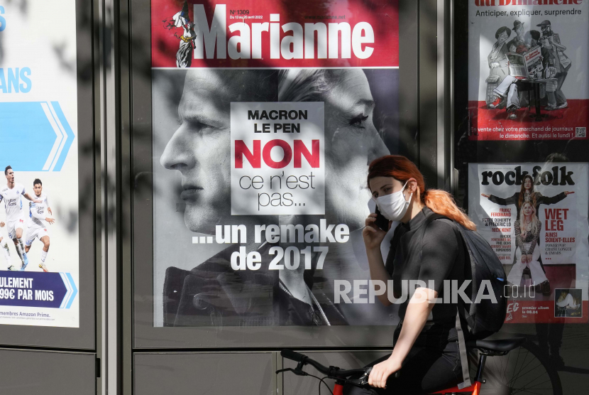 Seorang wanita melewati halaman depan majalah yang menjadi headline pada duel antara Presiden Prancis dan kandidat tengah untuk pemilihan kembali Emmanuel Macron dan pemimpin sayap kanan Marine Le Pen dalam pemilihan presiden, Kamis, 14 April 2022 di Paris.
