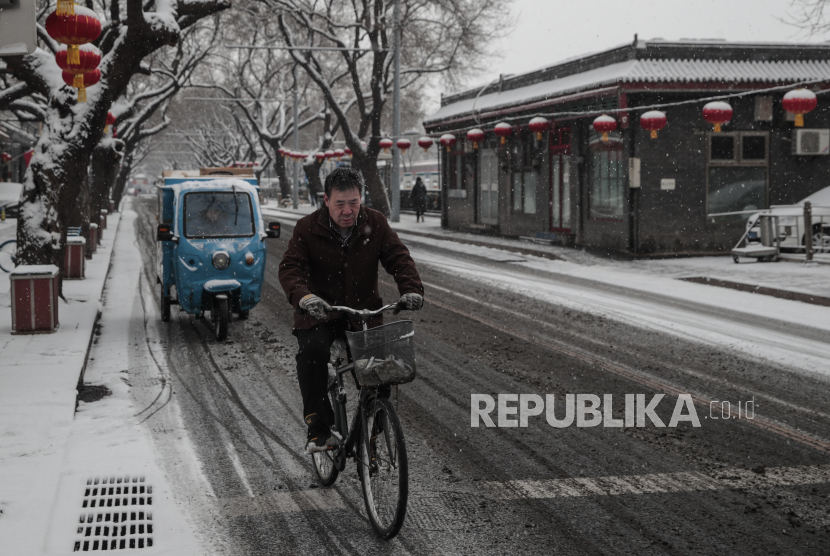 Seorang pria mengendarai sepeda saat hujan salju di Beijing, Cina, 13 Februari 2022. 