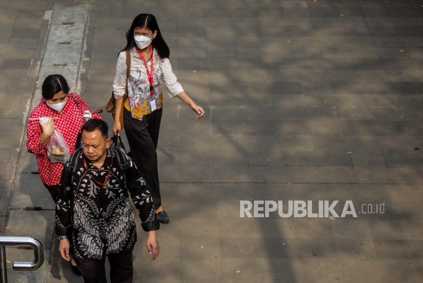 Pekerja memakai busana batik saat berjalan di kawasan Sudirman, Jakarta, Senin (2/10/2023).