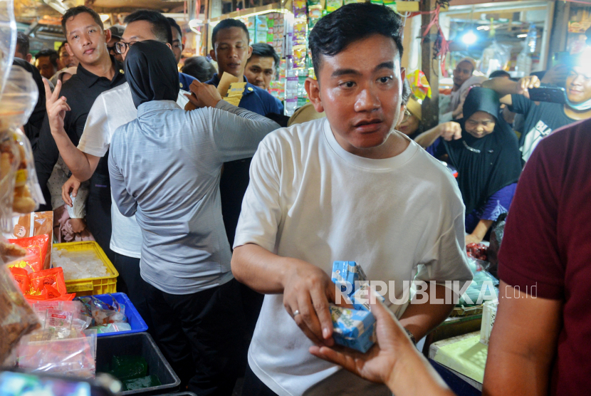 Cawapres nomor urut dua Gibran Rakabuming Raka membagikan susu kepada warga saat mengunjungi Pasar Rawasari, Cempaka Putih, Jakarta Pusat, Ahad (3/12/2023).
