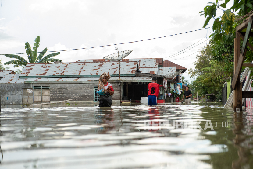 Sejumlah warga melintasi banjir yang melanda Kampung Tibang, Kecamatan Pidie, Kabupaten Pidie, Aceh, Minggu (22/1/2023). Banjir tersebut disebabkan tingginya intensitas hujan di kawasan tersebut dan buruknya drainase. 