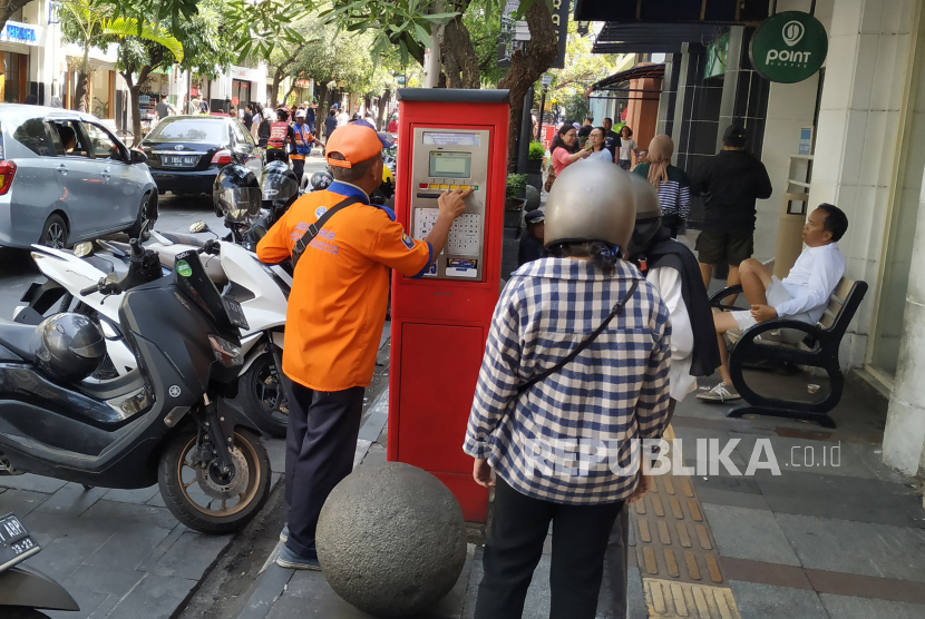 Juru parkir (Jukir) membantu warga membayar parkir dengan sistem elektronik di Jalan Braga, Kota Bandung, Senin (5/5/2023). 