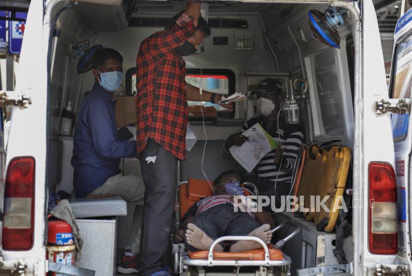 Sejumlah kerabat mendampingi pasien Covid-19 di dalam mobil ambulans saat menunggu untuk dirawat di luar rumah sakit pemerintah Covid-19, Ahmedabad, India, Selasa (27/4). Penuhnya rumah sakit membuat para pasien Covid-19 terpaksa harus dirawat di dalam ambulans. Tercatat angka kematian di India akibat virus Covid-19 telah mencapai 200.000 jiwa. (AP Photo/Ajit Solanki)
