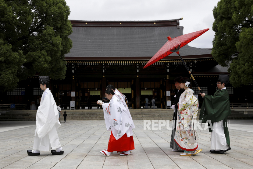 Pendeta Shinto dan gadis kuil memandu pasangan menuju aula upacara pernikahan kuil Meijijingu di Tokyo, Jepang, Sabtu (5/6). Kasus harian Covid-19 di Jepang turun secara dramatis menjadi beberapa ratus per hari. 