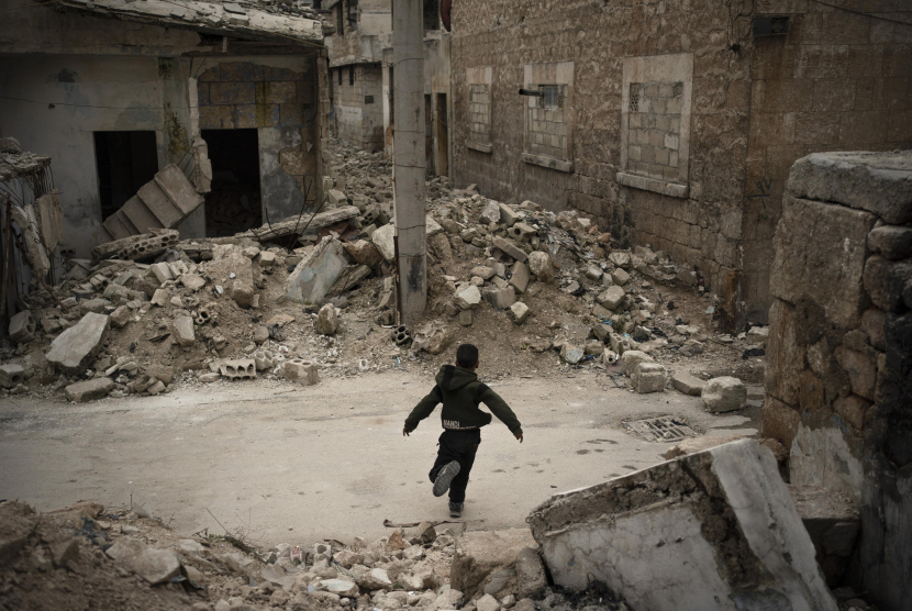 Seorang anak bermain di dekat rumah yang hancur akibat serangan udara di kota Idlib, Suriah. (AP Photo/Felipe Dana)
