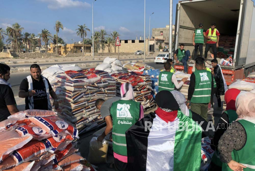 Orang-orang memasukan bantuan kemanusiaan ke Jalur Gaza kedalam truk yang diparkir di Arish, Mesir, Senin (16/10/2023).